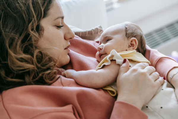 Mother cradling infant in bed