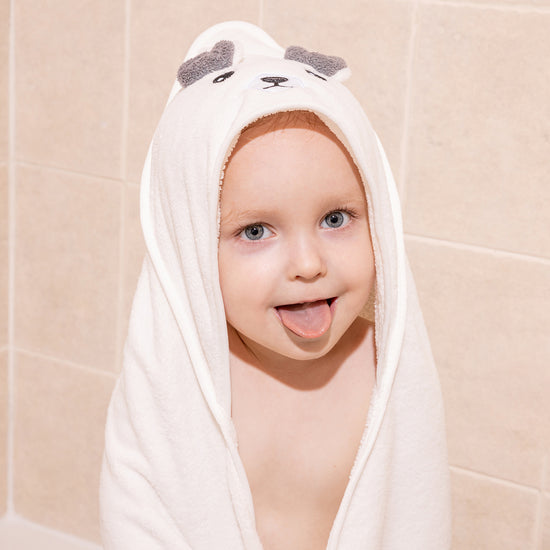 Child after a bath with their tongue sticking out wearing a Canopy bear baby towel