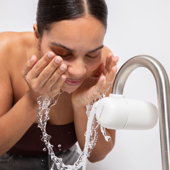 Model washing face by splashing water on to her face from the Faucet Filter in White