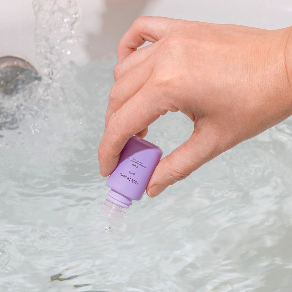 Hand dripping Calm Aroma Oil into the bath water