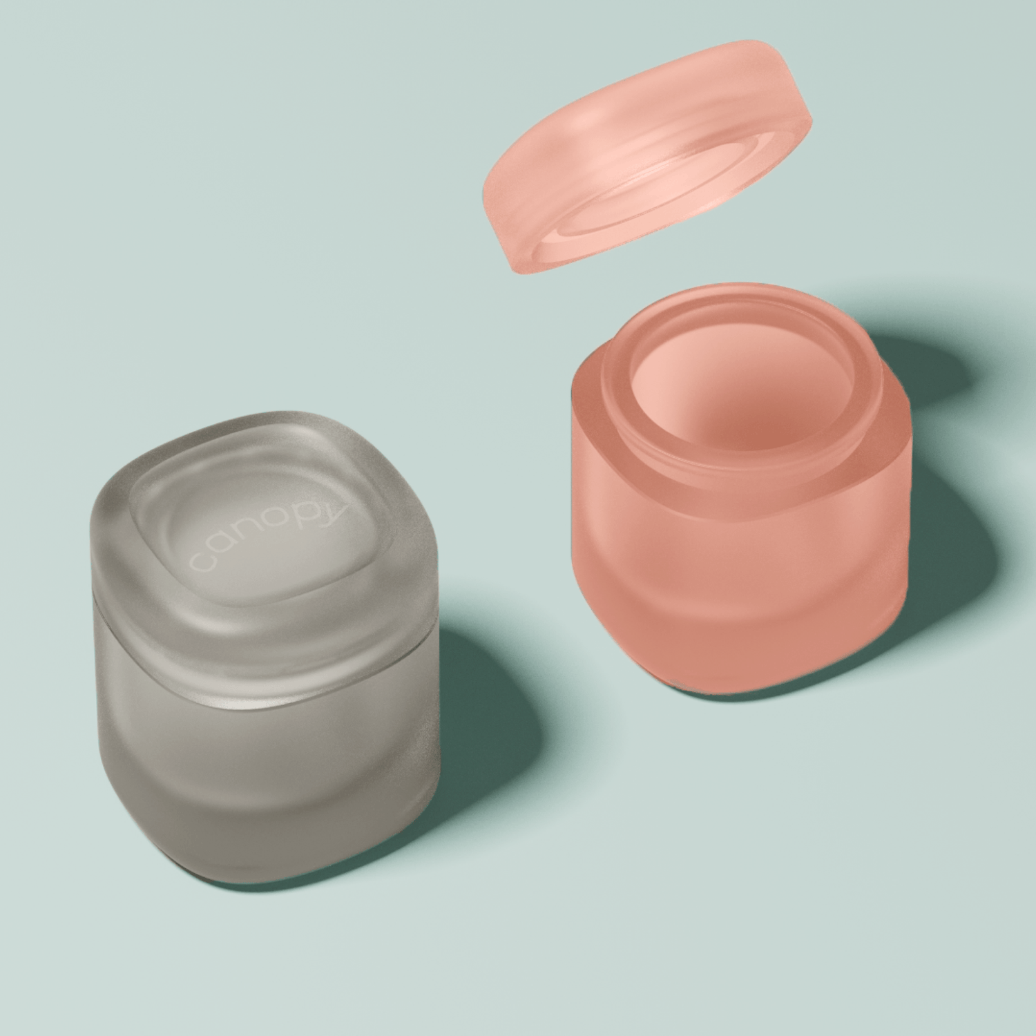Sleek and stylish Travel Containers in soft coral pink and matte grey, featuring frosted glass design with secure twist-off lids. Perfect for carrying skincare essentials and beauty products while traveling. By Canopy.