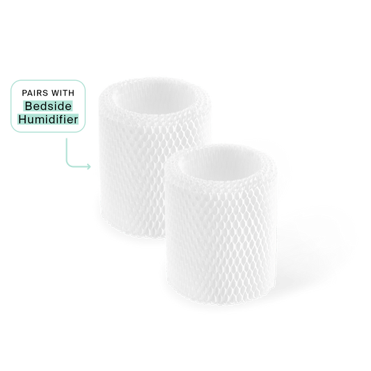 Bedside Humidifier Filter 2-Pack: Two cylindrical white antimicrobial replacement filters with honeycomb texture pattern, designed for efficient water filtration and evaporation. Text bubble indicates compatibility with Bedside Humidifier model.