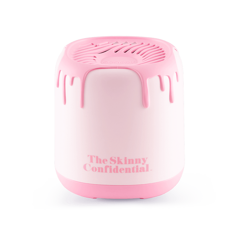The Skinny Confidential Aroma Diffuser featuring a pink and white compact design with drip-style top detail, sleek cylindrical shape, and branded text. Modern waterless diffuser with minimalist aesthetic by Canopy.