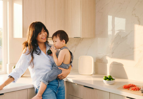 Woman in modern kitchen holding young child in front of cream Canopy Air Purifier
