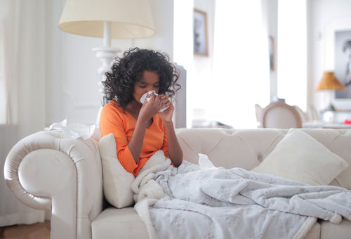 Woman on sofa with blanket and tissues