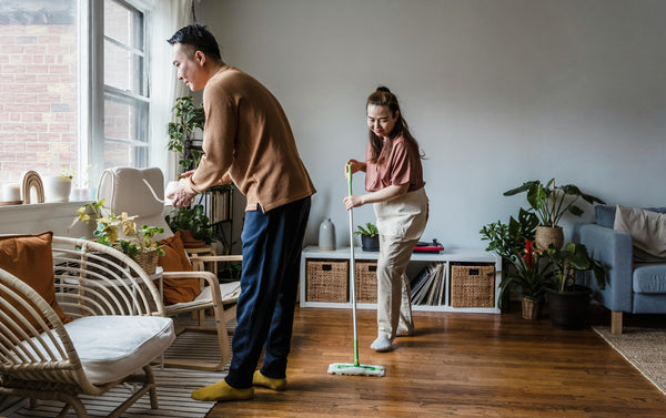 Man and woman cleaning apartment and watering house plants on a sunny day