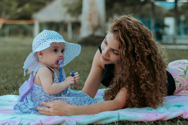 Mother and baby lying on blanket in the grass