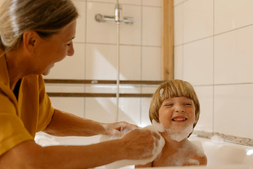 Grandmother helping grandson with bubble bath