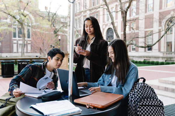 Three college students sitting outside school building