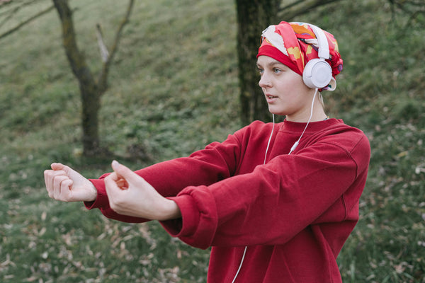 Young woman in activewear and a head wrap with headphones preparing for a run outdoors