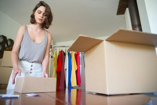 Young woman packing clothing into boxes