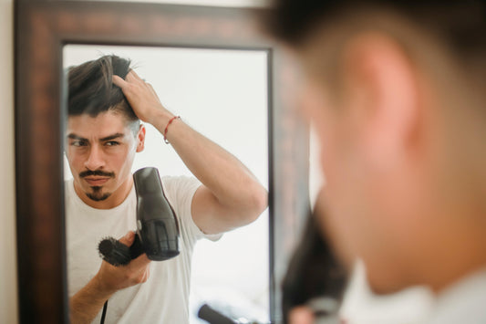 Man drying hair and checking scalp in the mirror