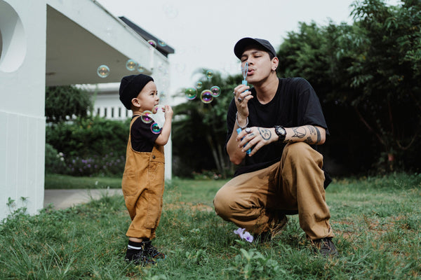 Father and son playing with bubbles in yard