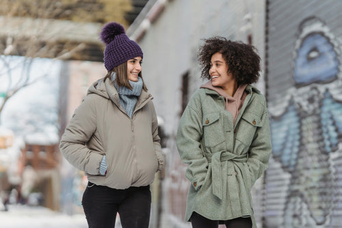 Two young women walking on city street in winter coats