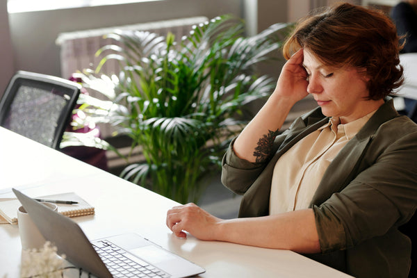 Woman sitting at desk feeling ill