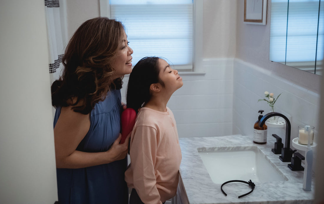 Woman brushing daughter's hair in bathroom