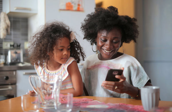 Mother and daughter in kitchen looking at phone screen