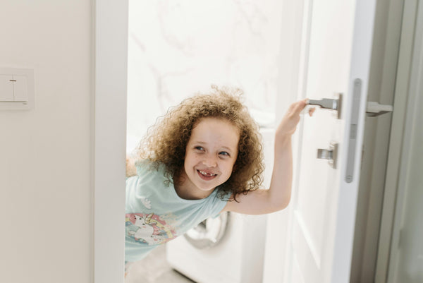 Young girl smiling in bathroom doorway