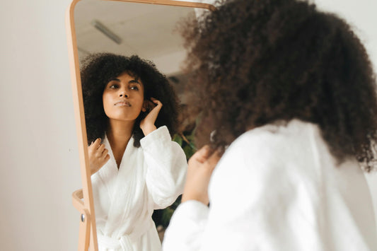 Woman in bathrobe checking hair in mirror