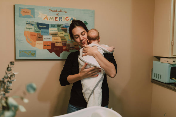 Woman cradling infant wrapped in towel after bath