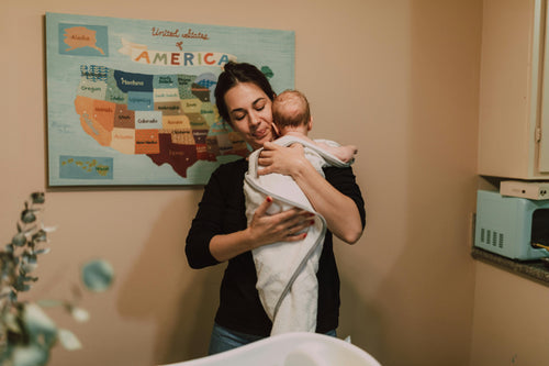 Woman cradling infant wrapped in towel after bath