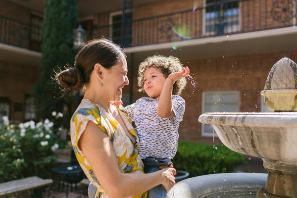 Mother and young son in courtyard next to fountain on sunny day