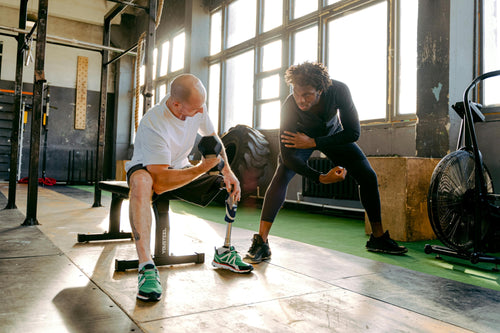 Man lifting weights in gym with trainer