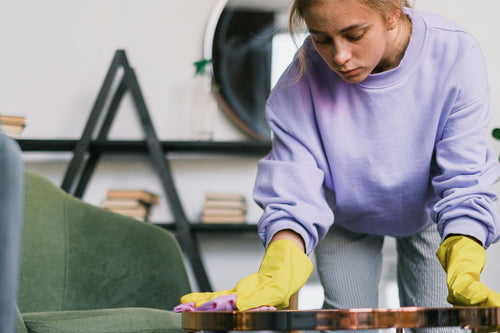 Young woman with rubber gloves cleaning living room