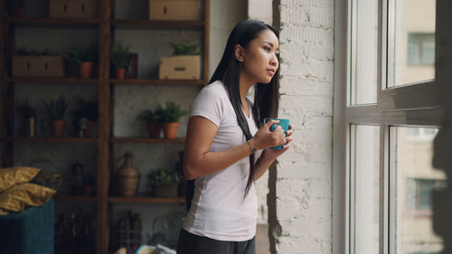 Woman looking out the window with coffee mug