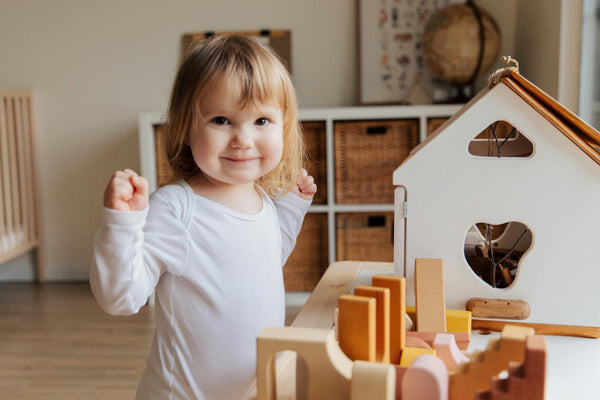Little girl in white pajamas playing with wooden toys