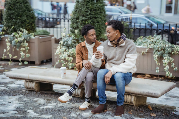 Men sitting on a park bench with coffee on a winter day