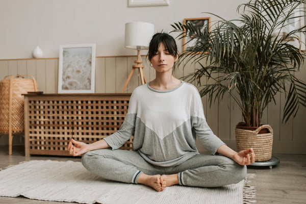 Woman meditating in relaxing room with houseplants and modern furniture