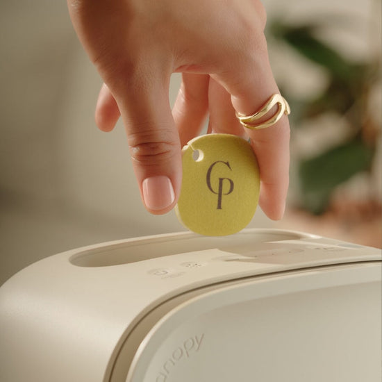 Clean Slate Aroma Kit | Lifestyle, Hand placing a yellow disc with 'CP' logo on a white device, blurred background