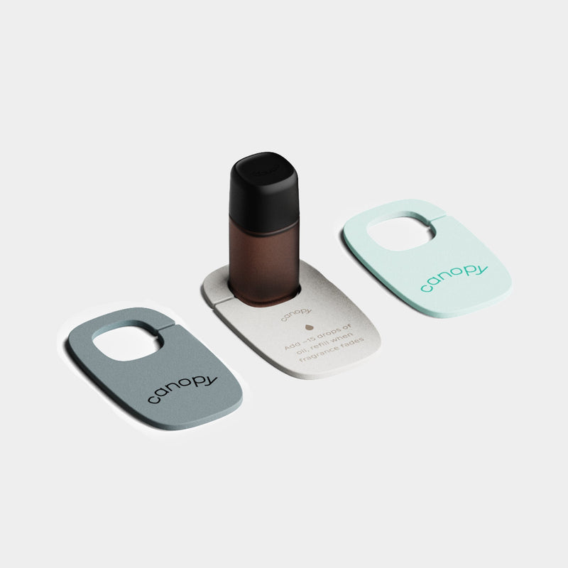 Felt Diffuser 3-Pack featuring three modern, sleek diffuser holders in mint green, silver, and gray colors, with a dark glass essential oil bottle positioned in the center. Minimalist design perfect for portable aromatherapy by Canopy