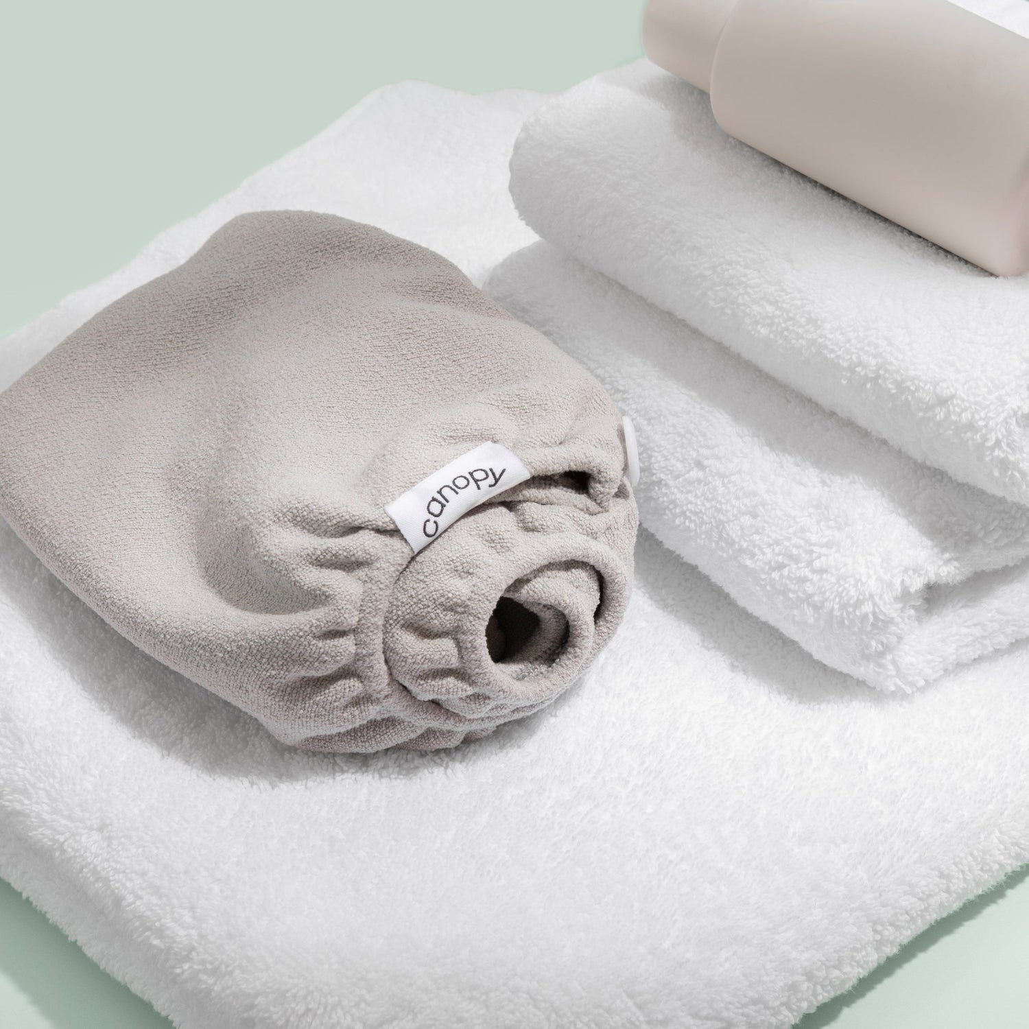 Hair Towel | In use, folded next to a stack of white bath towels