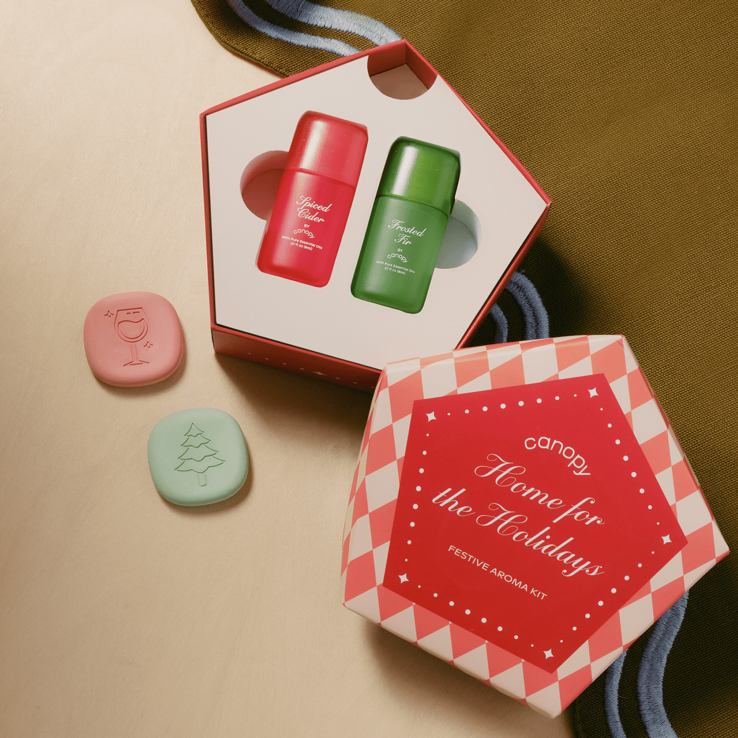 Home for the Holidays Aroma Kit with red and green bottles and pink and green stones on a beige background