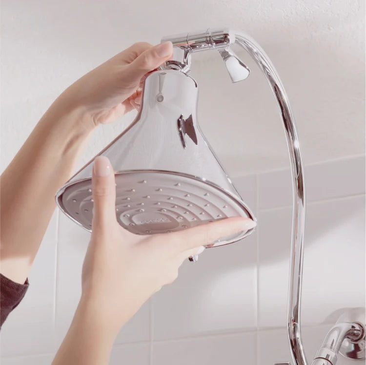 Person holding a shower head with a tiled bathroom background