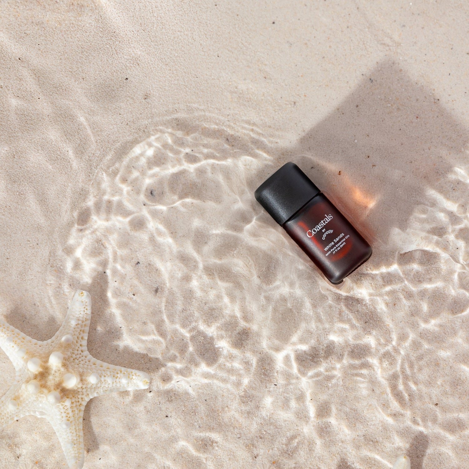 White Sands Aroma | Lifestyle, Aroma Bottle pictured on wet sand with clear water