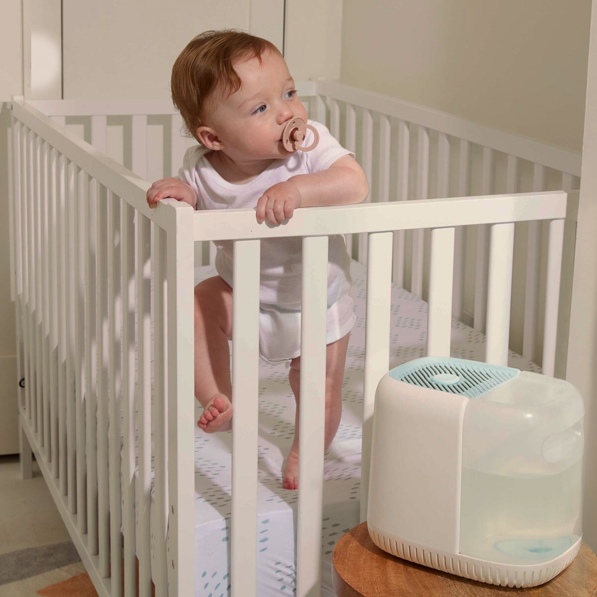 Nursery Humidifier | Lifestyle, Baby in a crib next to a blue Nursery Humidifier